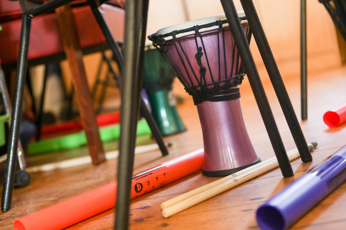 An array of percussion instruments including an African drum on the floor of a workshop. 